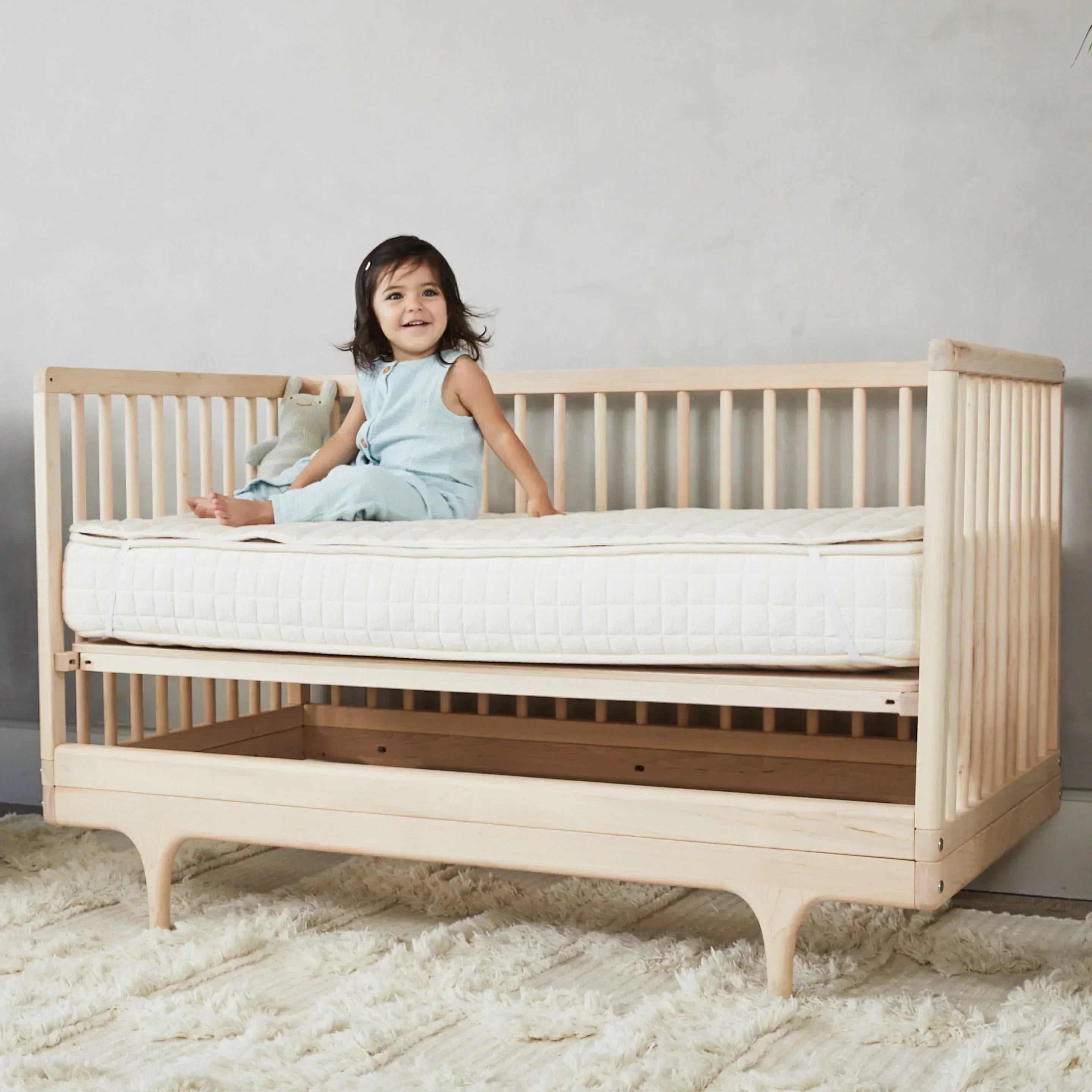 baby girl is sitting on Crib Mattress