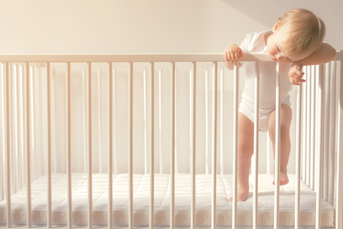 Baby standing in crib. Poppyseed Play