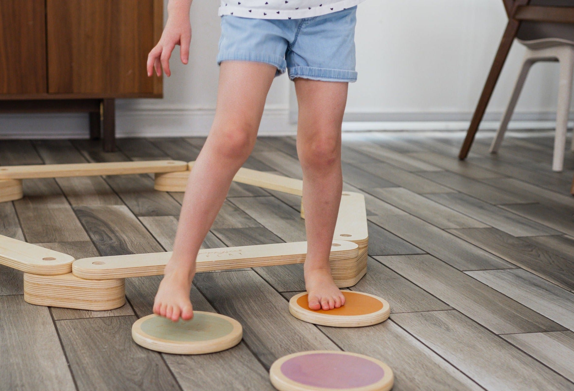 Children walking across a path of wood stepping stones.