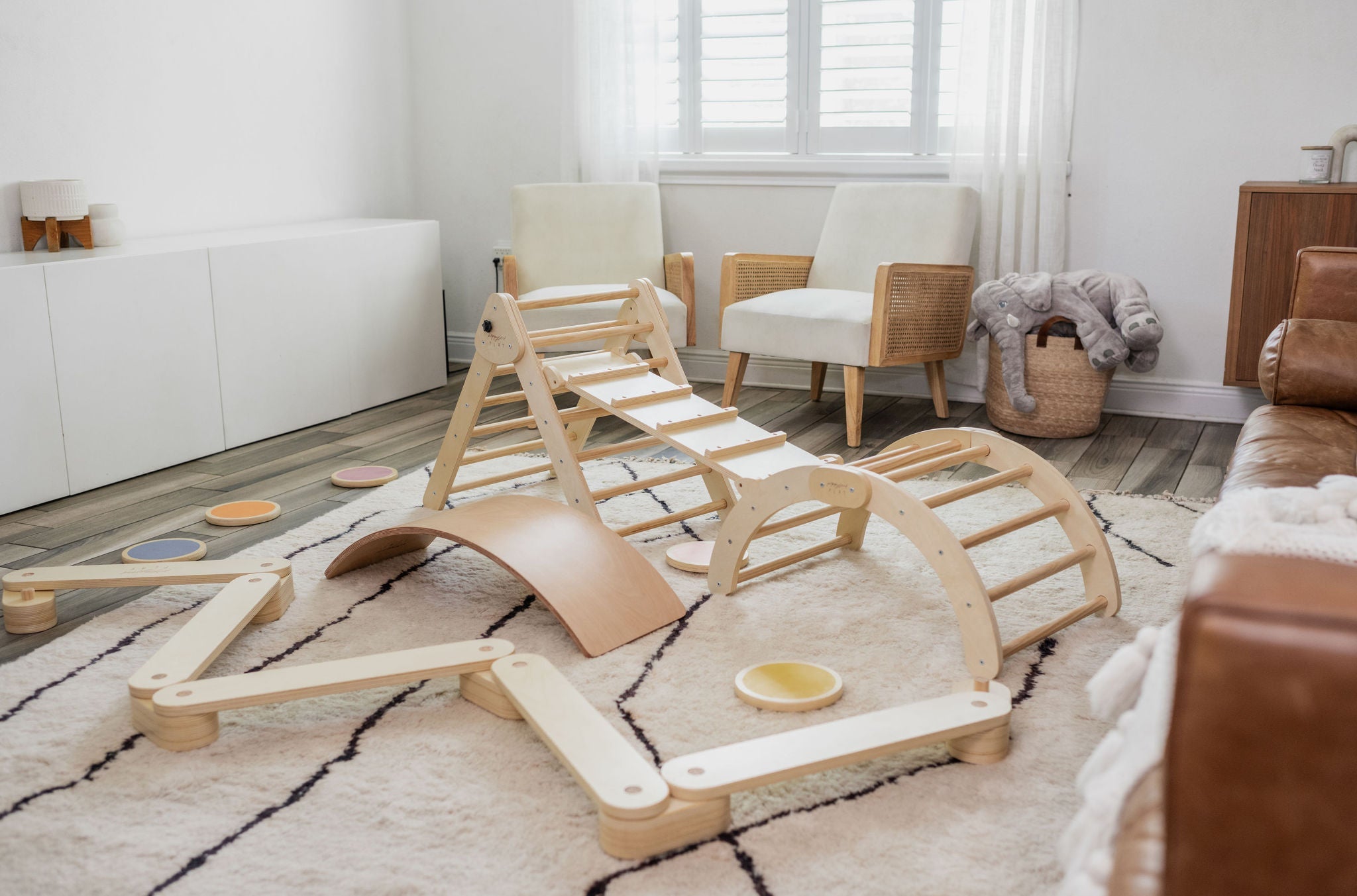 Play gym sets featuring a Montessori climber, climbing arch, wooden balance board, and wooden balance beam in a living room.