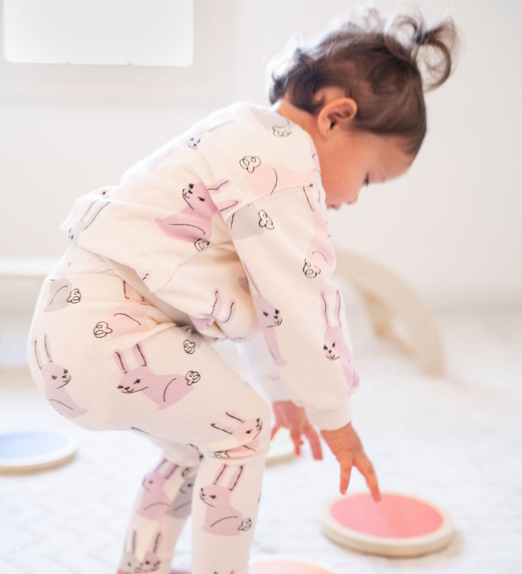 Toddler in bunny pajamas balancing on Wood Stepping Stones on a soft white rug