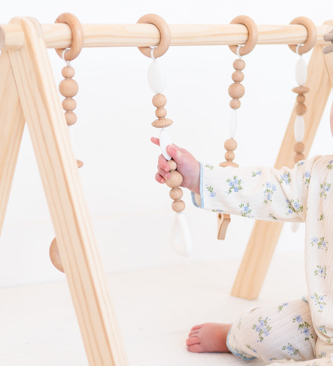 Baby playing with a wooden climbing toy on a white background