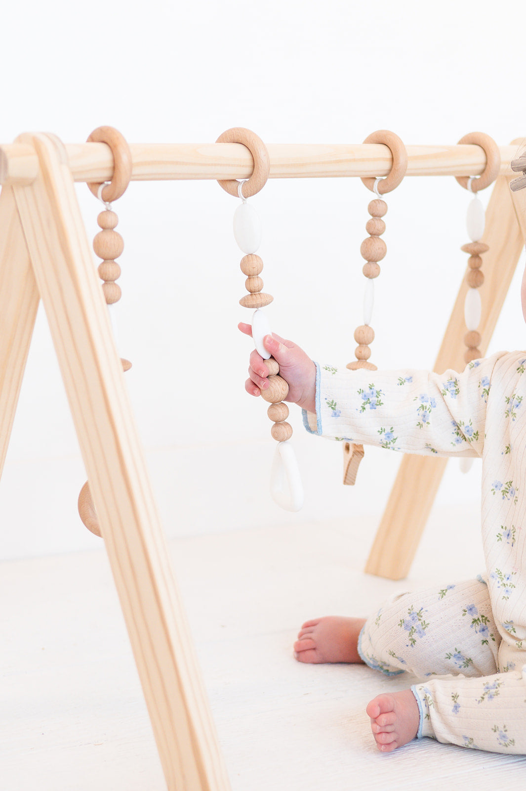 Baby playing with a wooden climbing toy on a white background