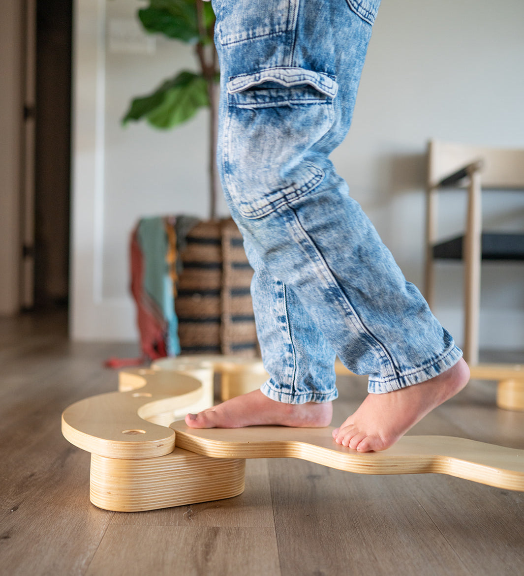Person standing on a wooden balance board in a home setting
