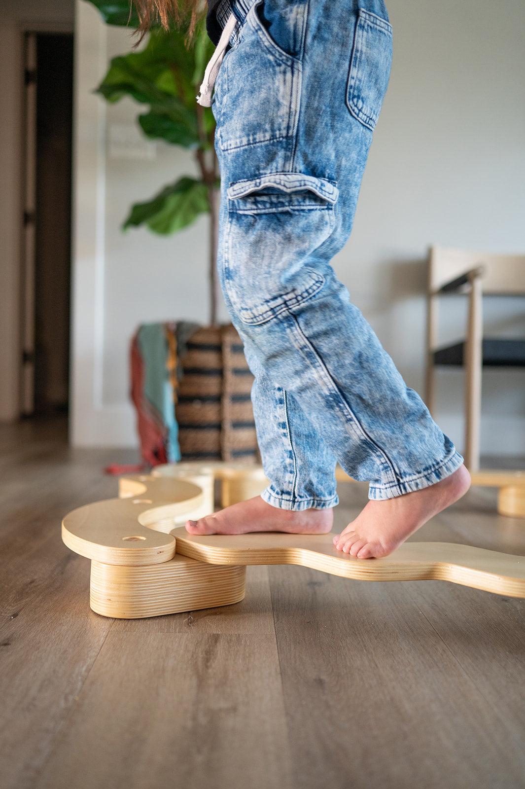Person standing on a wooden balance board in a home setting