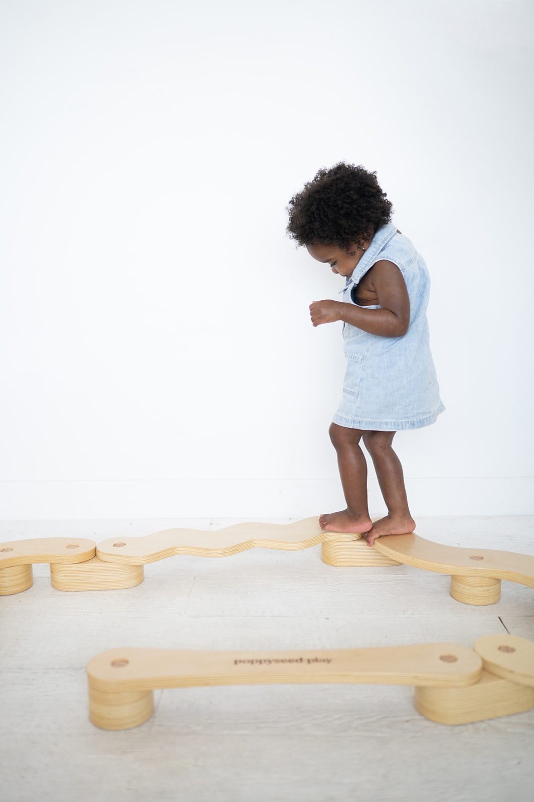 Child playing with a wooden balance toy on a white background