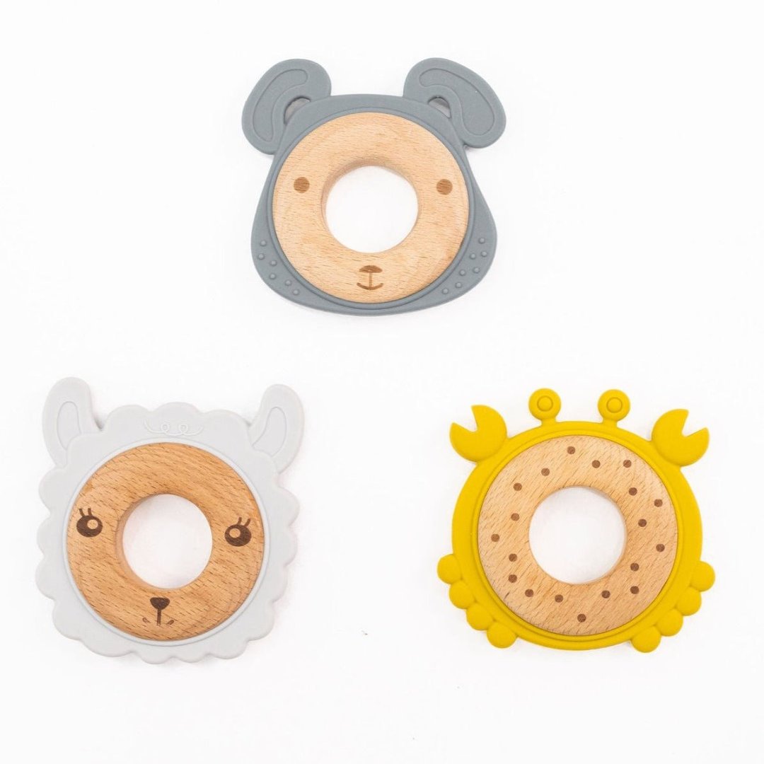 A set of three teethers in different animal designs: a bear, a sheep, and a lion, each with a wooden ring in the center and a soft silicone outer part.
