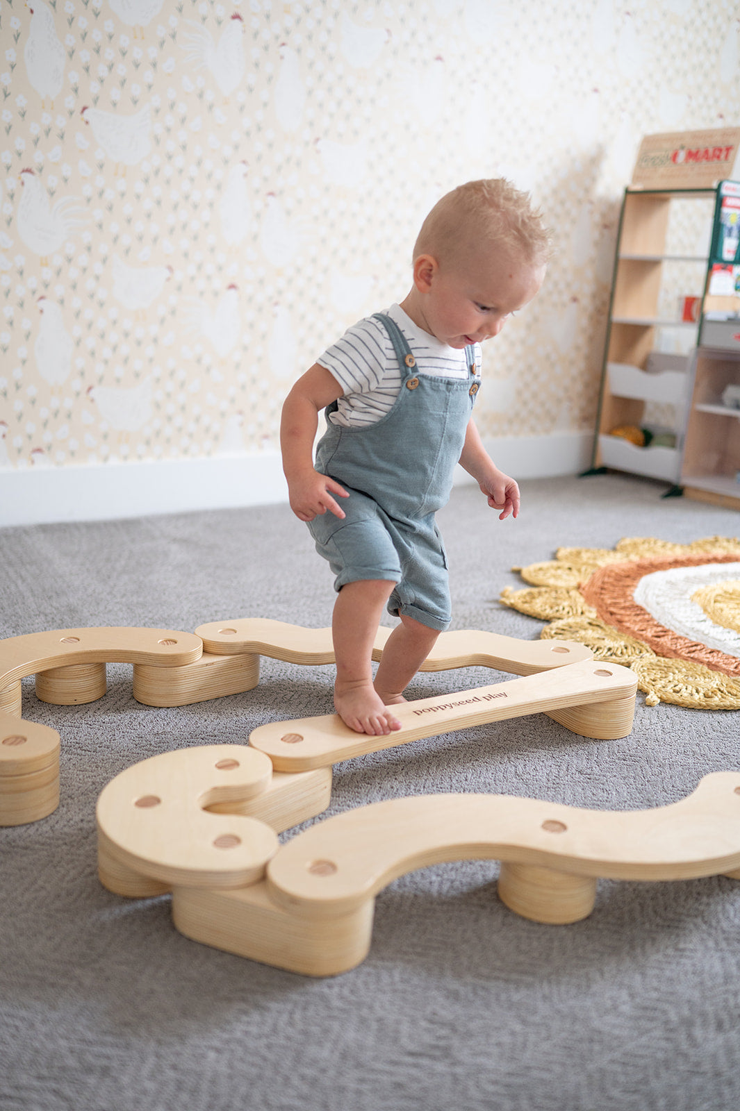 Child playing with wooden train tracks on a carpeted floor.
