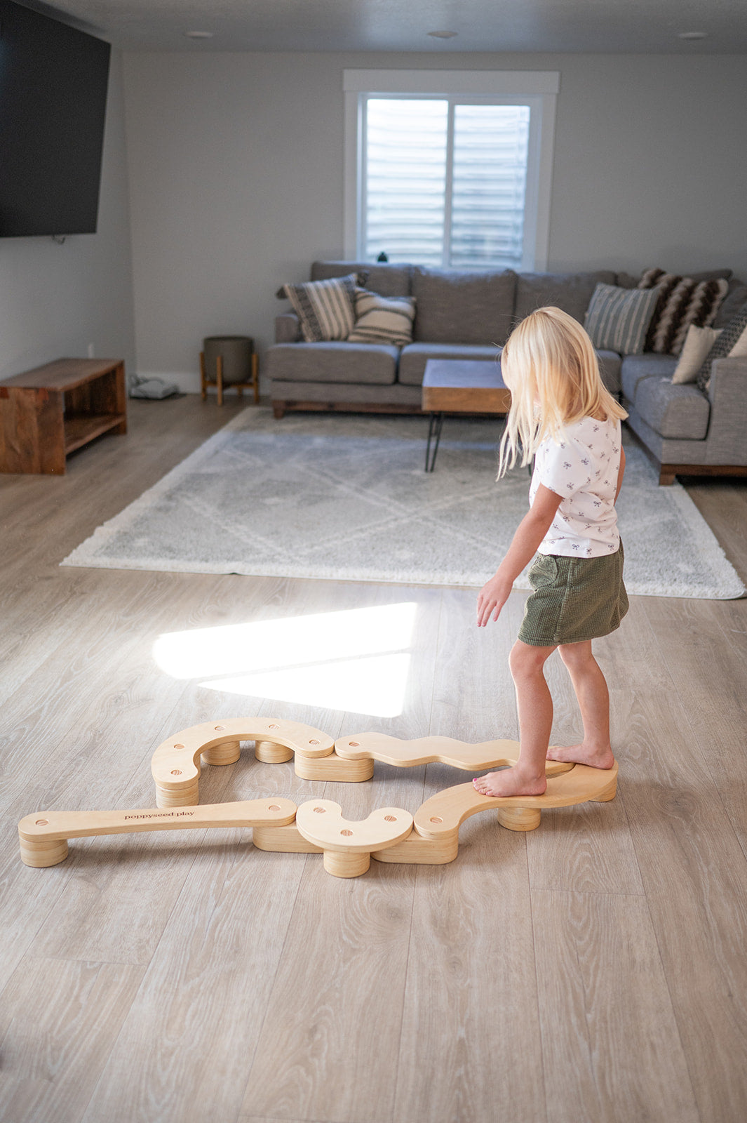 Child playing with a wooden balance toy in a living room.