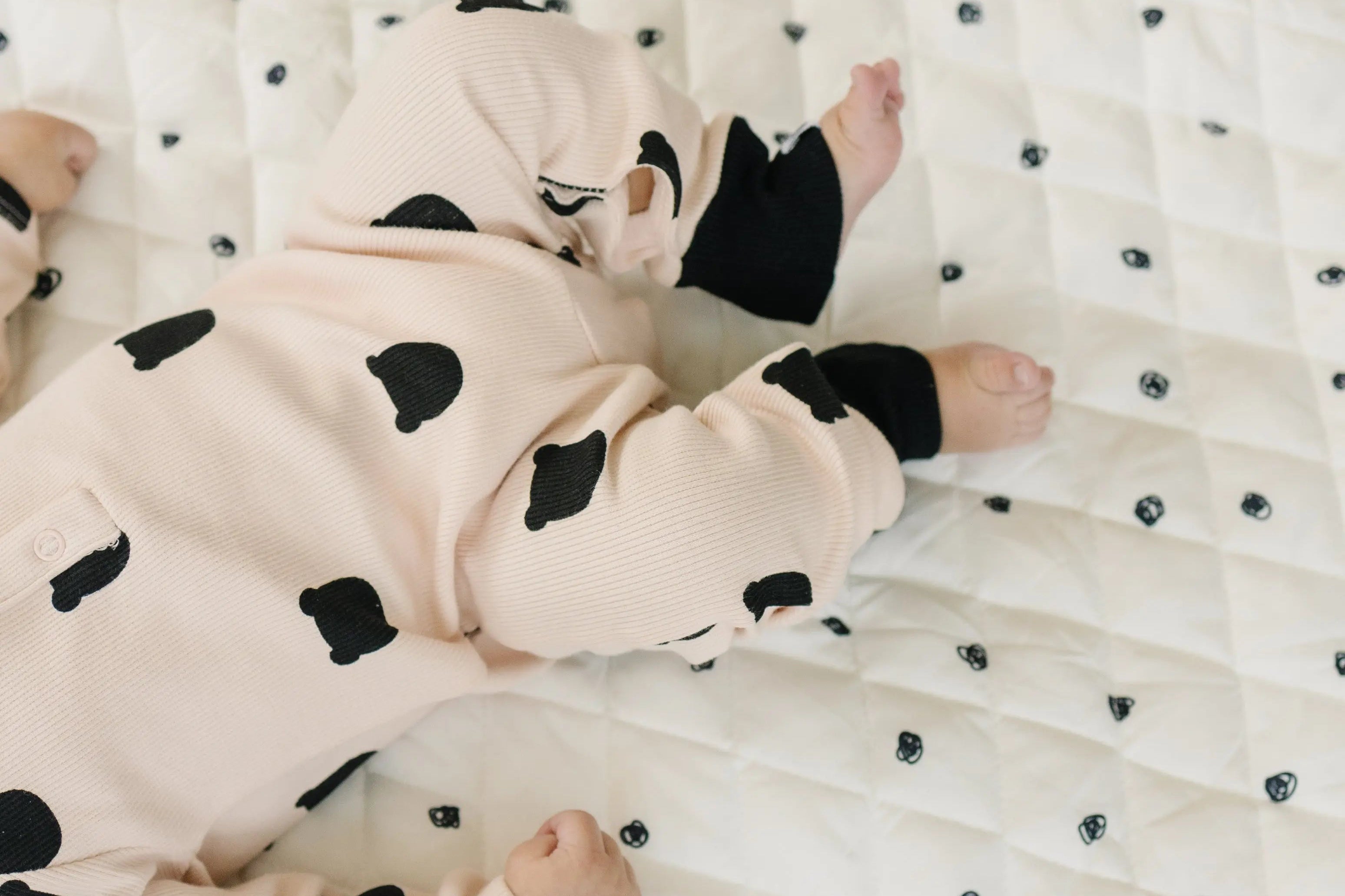 Baby reaching for high-contrast black and white toys on a stylish, modern play gym set.