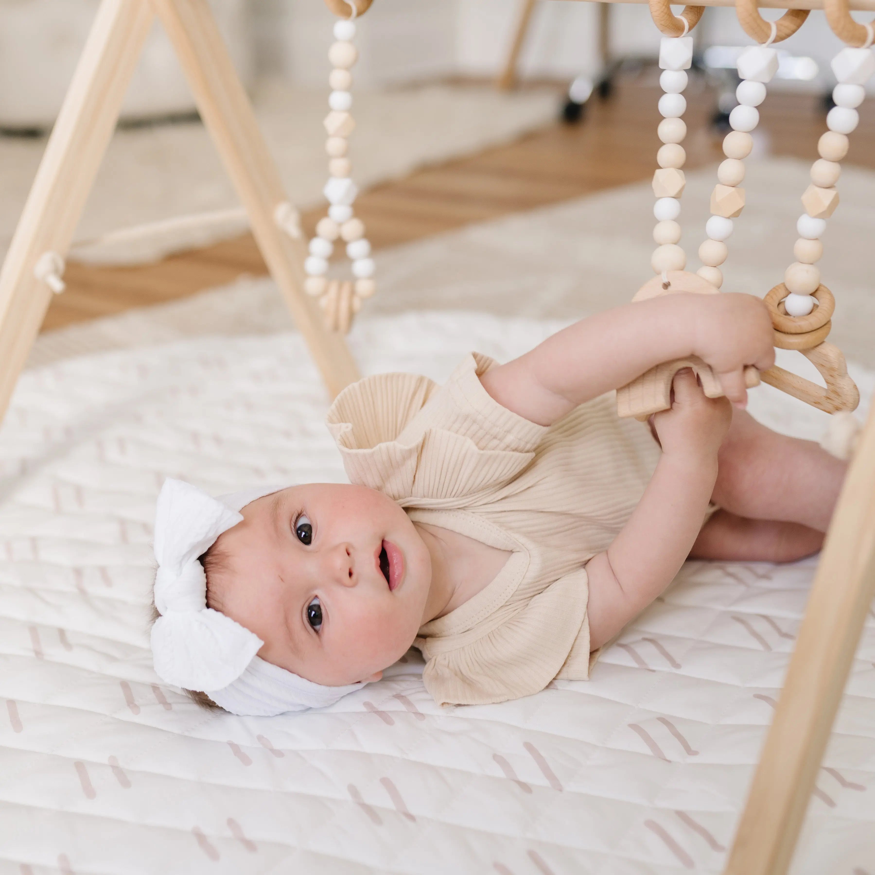 Stylish play gym set featuring a blend of neutral and white colors, perfect for any nursery decor.