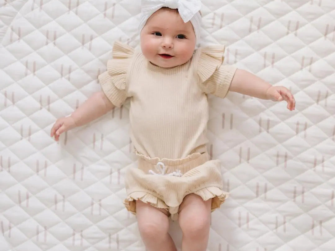 Minimalist neutral and white play gym with plush, versatile toys for interactive play