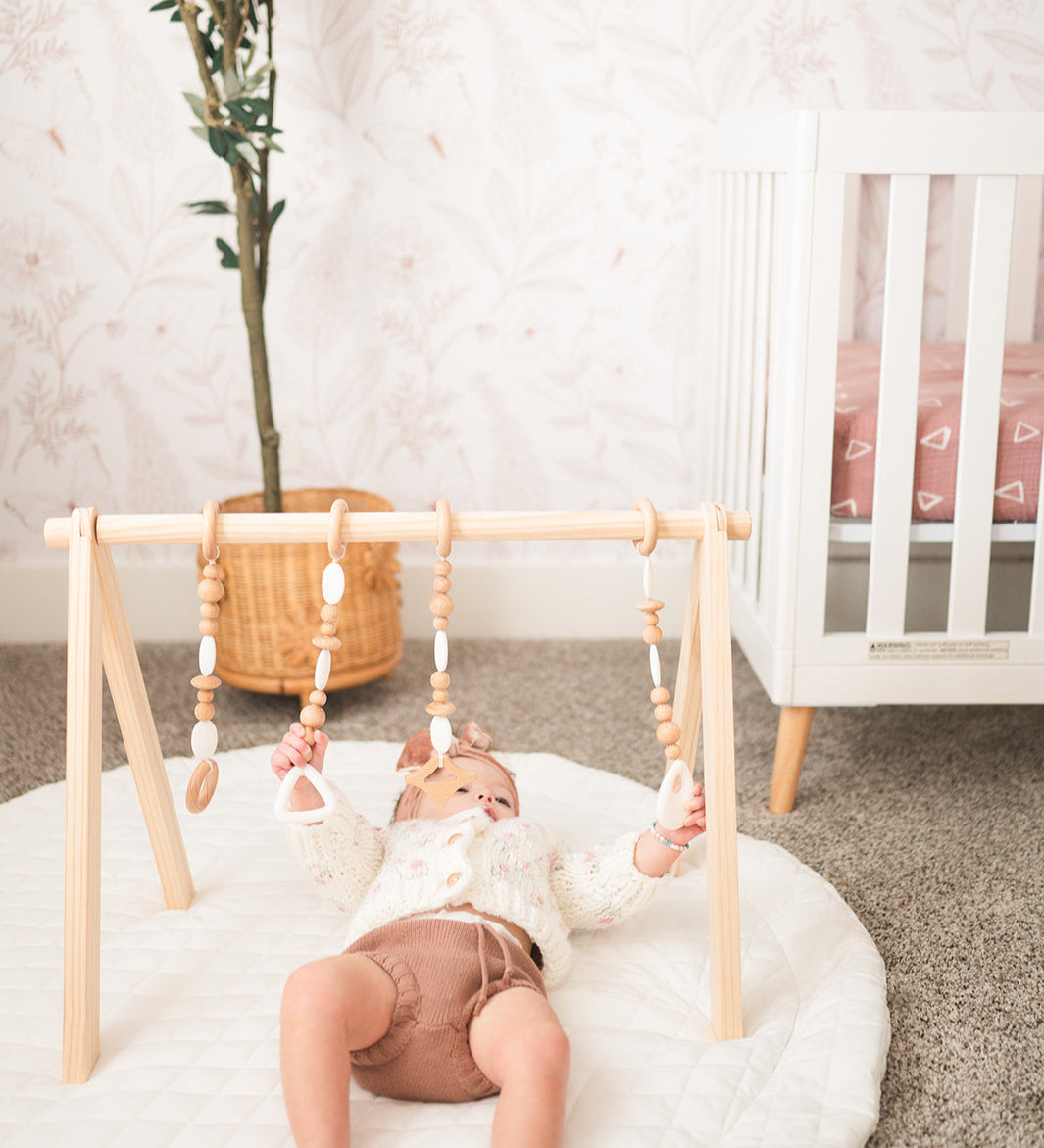 Child playing with a wooden baby gym in a nursery.