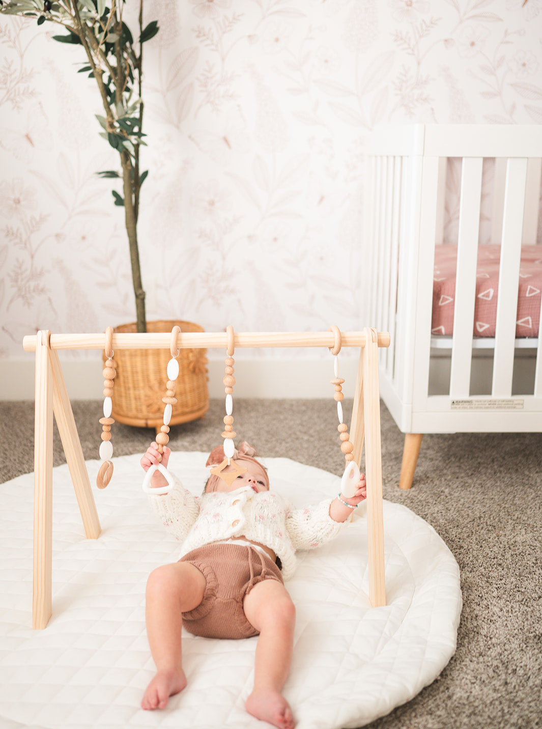 Child playing with a wooden baby gym in a nursery.