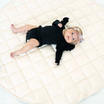 Baby lying on the blush Neutral Round Baby Play Mat