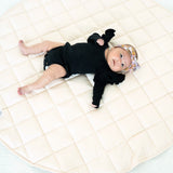 Baby lying on the blush Neutral Round Baby Play Mat