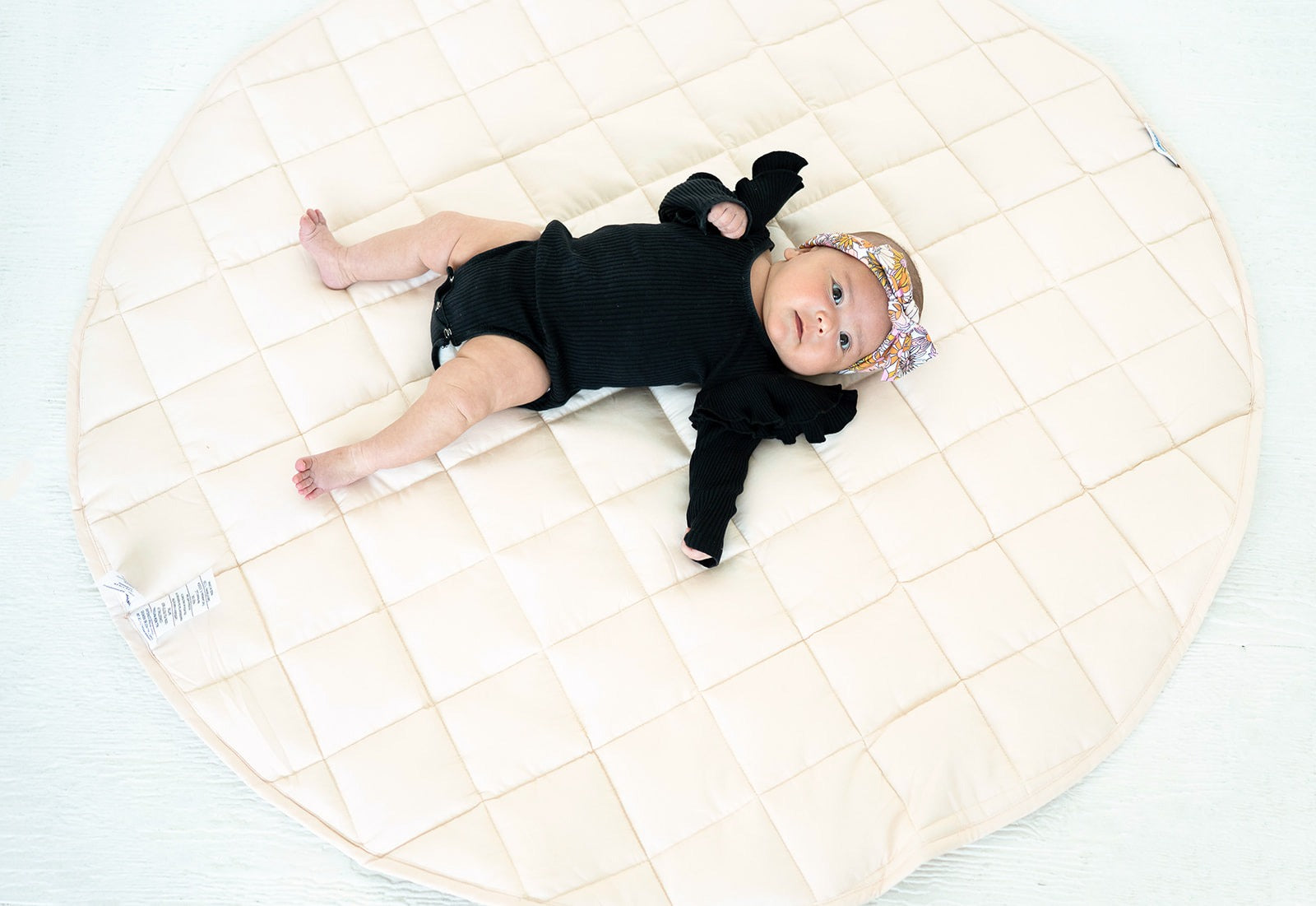 Baby lying on the blush Neutral Round Baby Play Mat