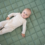 Baby lying on the olive green Neutral Round Baby Play Mat