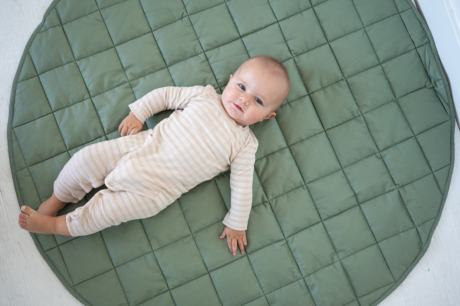 Baby lying on the olive green Neutral Round Baby Play Mat