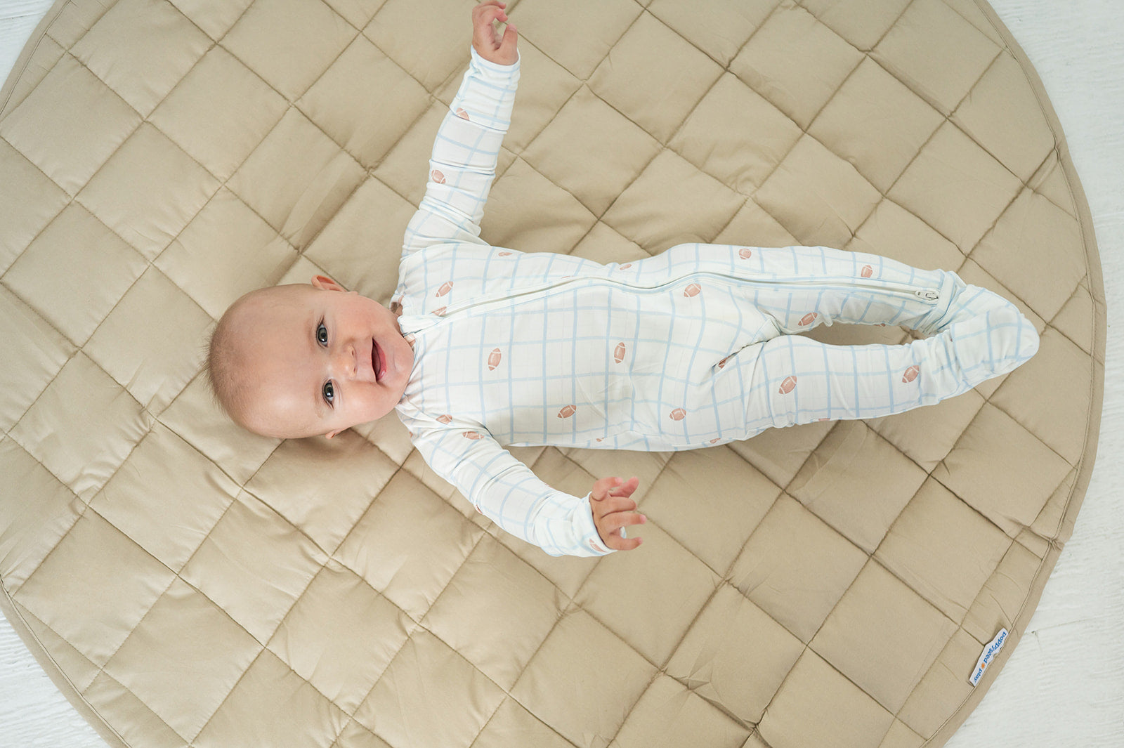 Baby stretched out on the taupe Neutral Round Baby Play Mat showing its 42 inch size