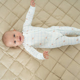 Baby stretched out on the taupe Neutral Round Baby Play Mat showing its 42 inch size