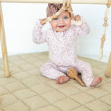 Smiling baby playing under a wooden baby gym on the taupe Neutral Round Baby Play Mat